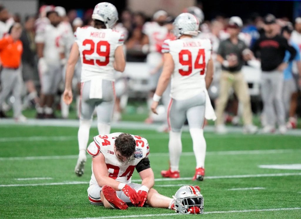 Atlanta, Georgia, USA; Ohio State Buckeyes tight end Mitch Rossi (34) sits on the ground after Ohio State Buckeyes place kicker Noah Ruggles (95) missed the game winning field goal during the fourth quarter of the Peach Bowl in the College Football Playoff semifinal at Mercedes-Benz Stadium.